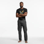 Man wearing a black t-shirt with a colorful design and gray pants on a white background