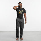 Man wearing a black t-shirt with a butterfly design and gray cargo pants on a white background